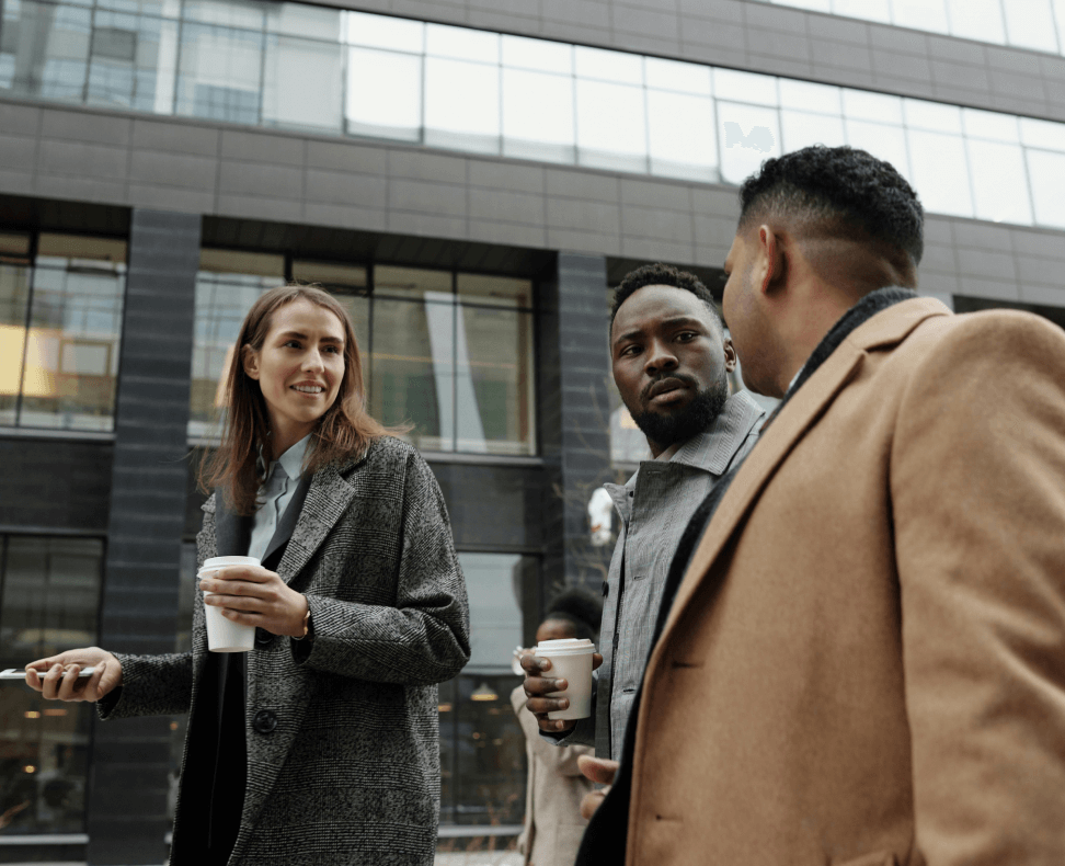Group of professionals discussing ideas outdoors with coffee, reflecting teamwork and collaboration in a thriving business with genuine professionals.