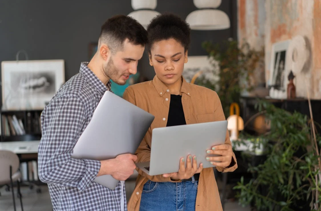 Two colleagues discussing ideas on a laptop in a modern office, representing teamwork and personal inspiration for creative projects.