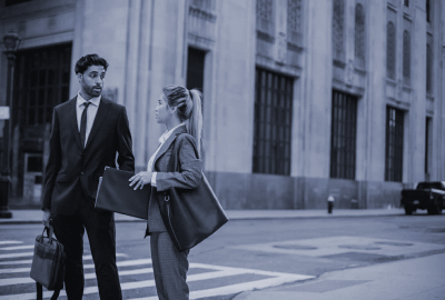 Two business consultants walking through a city street, deep in conversation on international business consulting strategies.