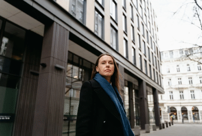 A confident professional standing outside a modern office building, symbolizing innovation and growth in E-Commerce and Market strategies.