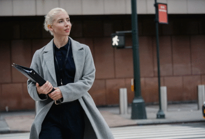 A professional woman walking confidently with documents, representing leadership and expertise in Human Resources and Management.