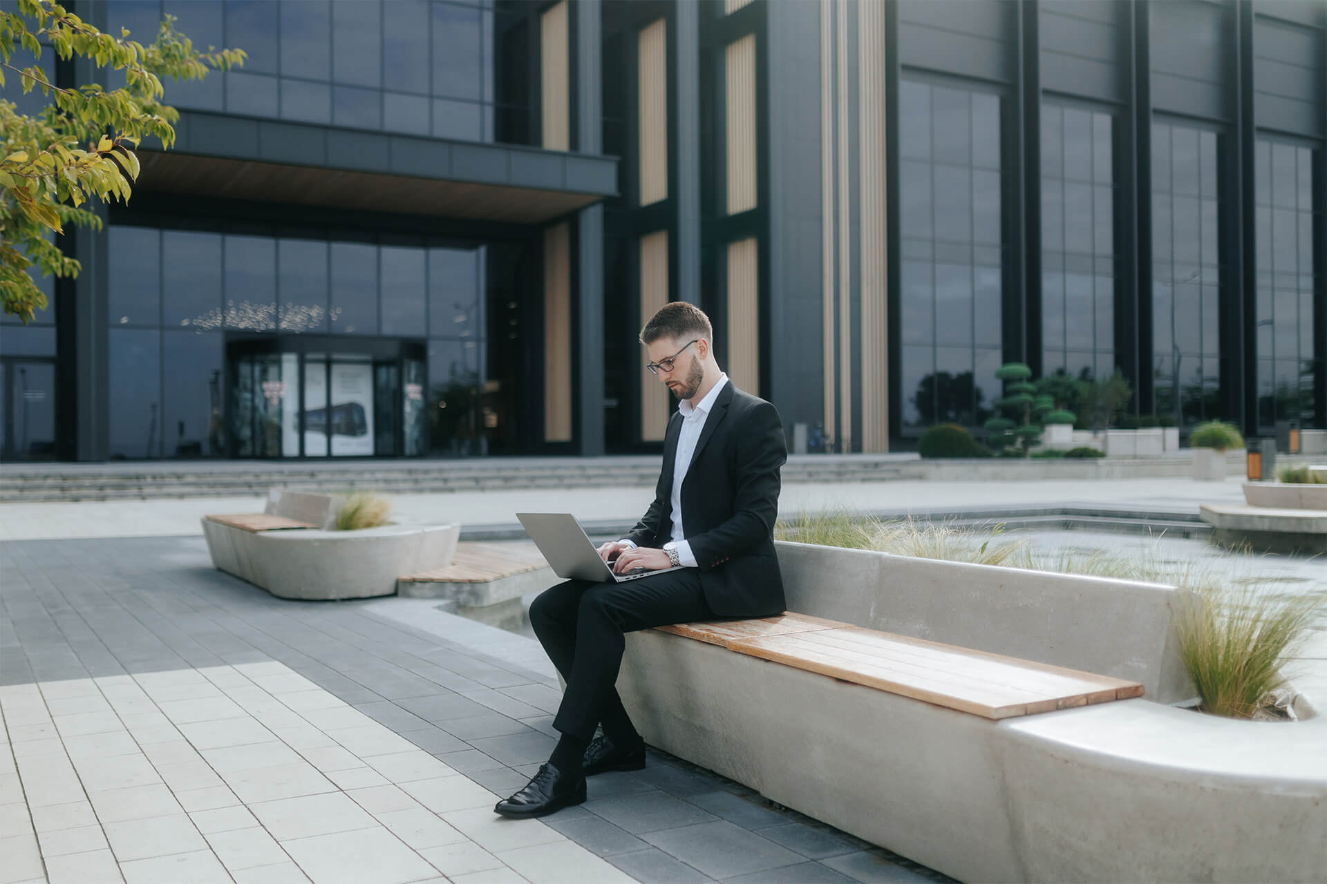 Business professional working on a laptop outside a modern office building, representing productivity and insights through Digital Analysis.