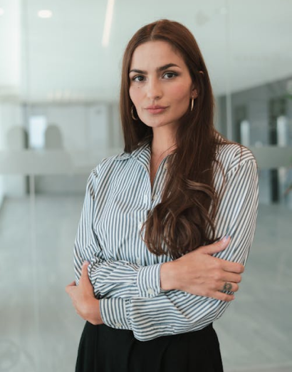 Confident businesswoman standing with folded arms in modern office, representing the professional and dedicated **uresucces team** focused on client growth.