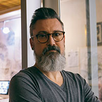 "Confident consultant with glasses and a gray beard standing in an office, representing expert advice and technical support tailored to organizational needs."