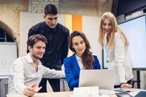 A team of professionals discussing ideas and analyzing data on a laptop, collaborating on Business Strategy and Planning in a modern office setting.