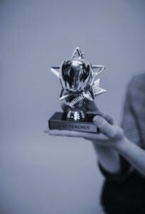 Person holding a shiny silver trophy, symbolizing achievement and recognition, representing a nominated agency as top of the best business agencies worldwide.